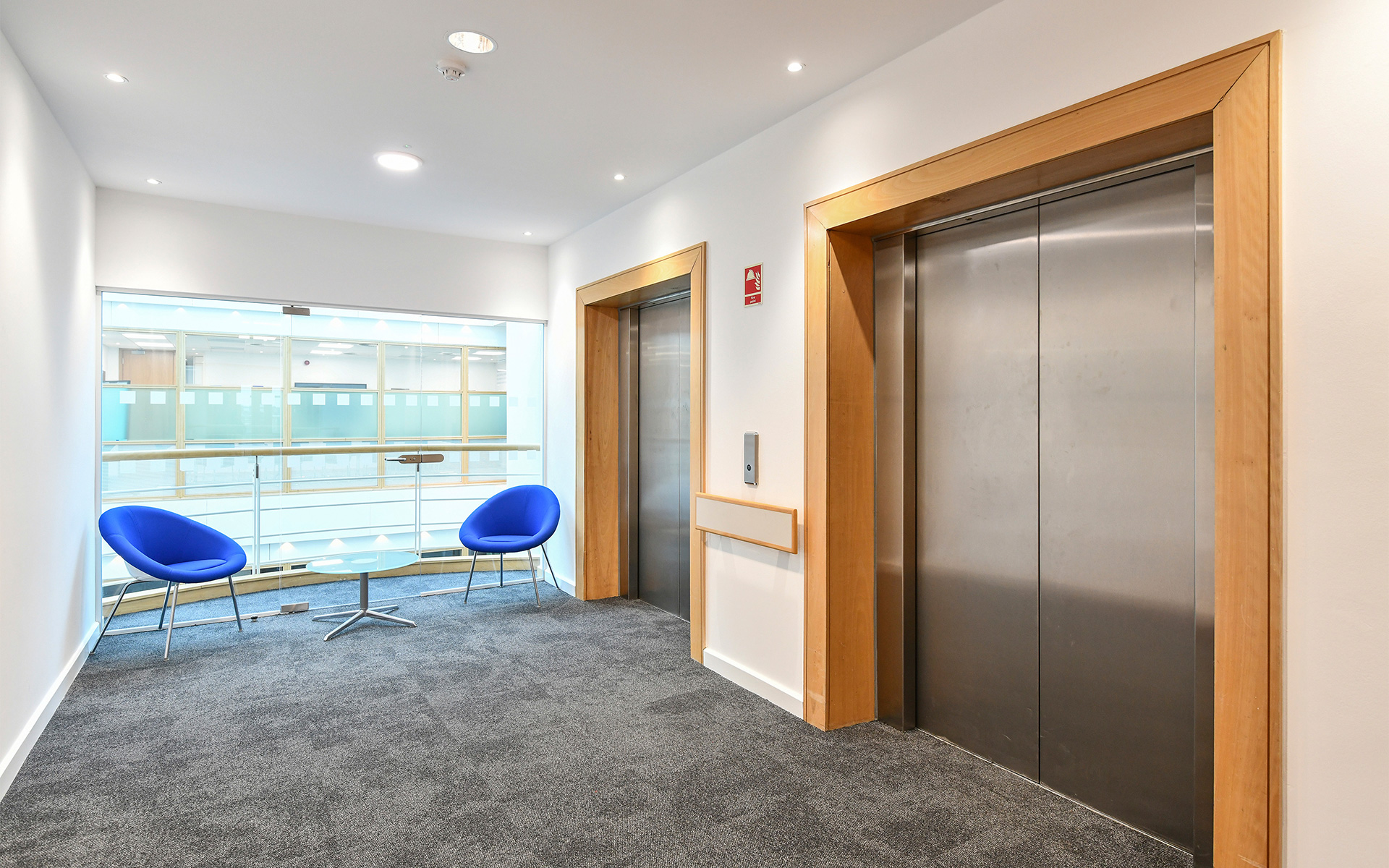 Elevators with seating area next to it at One Trinity Park.